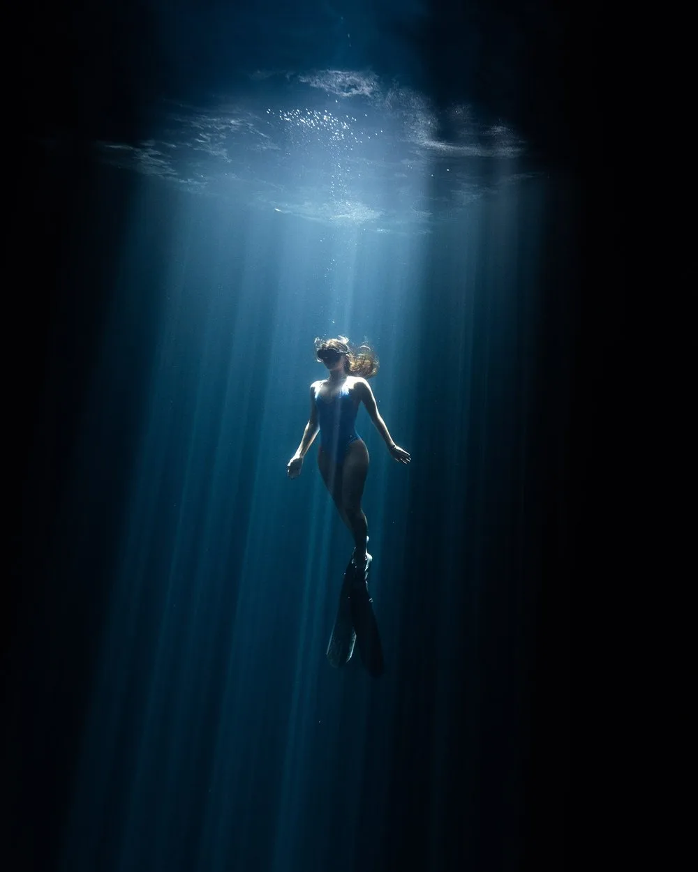Freediver suspended in a beam of light underwater